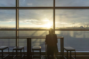 UK, London, Rückansicht einer Frau im Flughafenterminal bei Sonnenuntergang - ISF24929