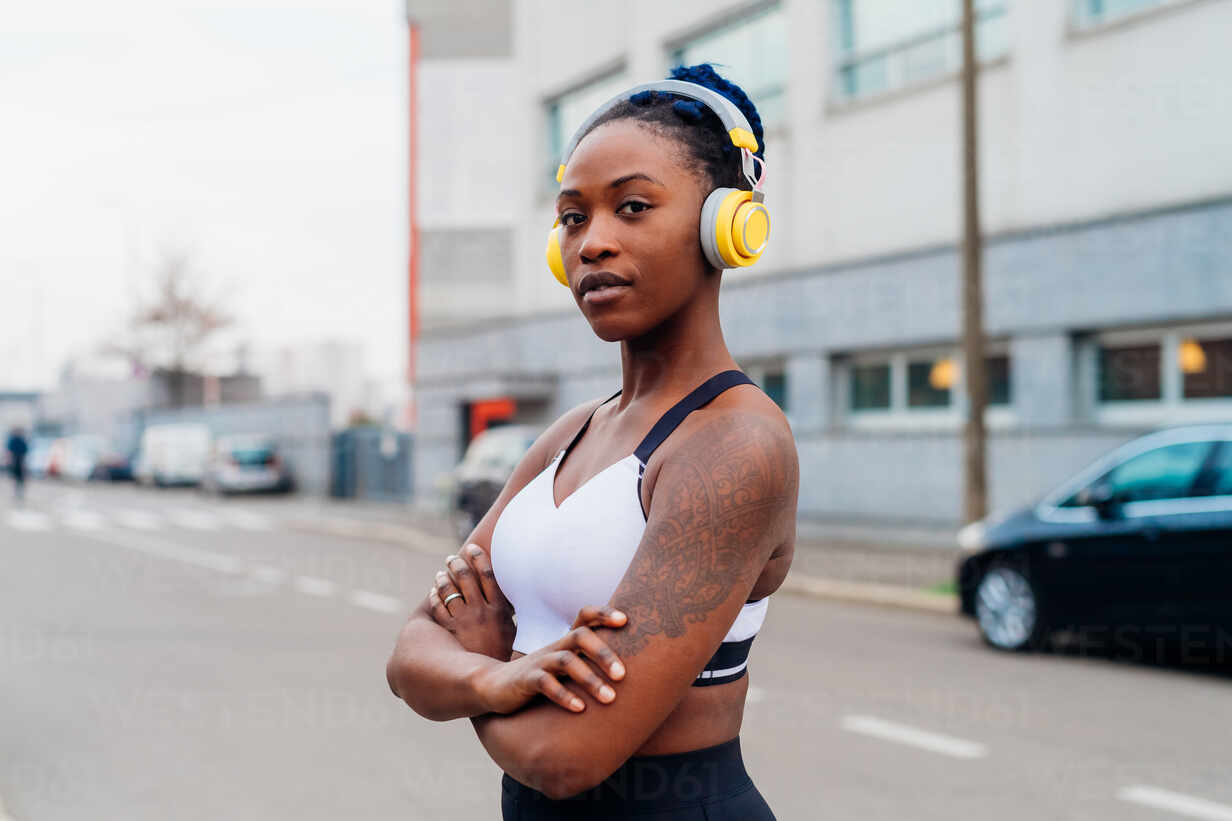 Italy, Milan, Portrait of woman in sports bra and headphones in city stock  photo