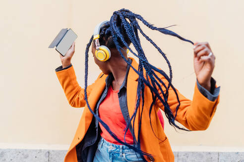 Italien, Mailand, Frau mit Kopfhörern und Smartphone tanzt im Freien - ISF25003