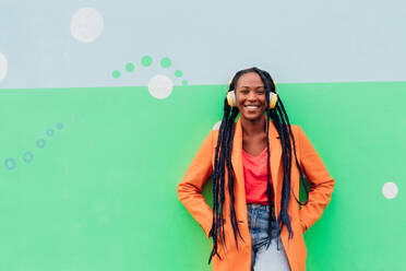 Italy, Milan, Portrait of stylish woman with headphones against wall - ISF25053