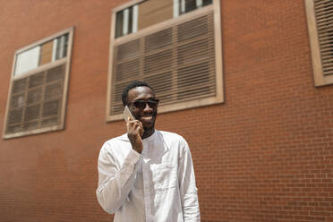 Young man talking on smart phone in front of building - MTBF01100