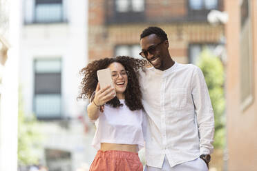 Happy man and woman taking selfie through smart phone - MTBF01115