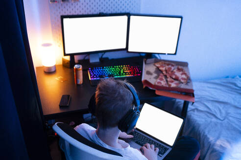 Gamer boy using laptop near table at home - VPIF04634