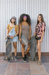 Drei schöne junge Frauen verschiedener Rassen mit ihren langen Brettern schauen in die Kamera - ADSF28771
