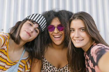 Drei schöne junge Frauen verschiedener Rassen mit ihren langen Brettern haben Spaß und schauen in die Kamera - ADSF28777