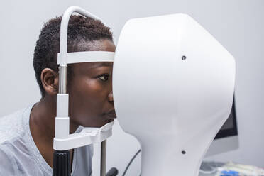 Black woman in optometry cabinet during study of the eyesight using a modern corneal topographer - ADSF28792