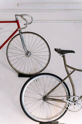 Old bikes hanging on background of white wall in repair service workshop at daytime - ADSF28838