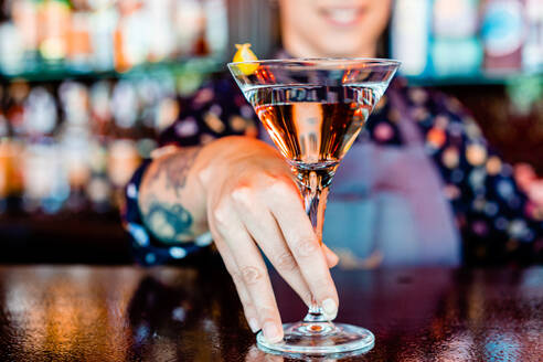 Anonyme fröhliche Barkeeperin mit einem Glas erfrischendem Wermut am Tresen einer Bar - ADSF28910