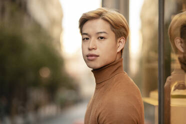 Seitenansicht eines gut aussehenden asiatischen männlichen Modells mit blondem Haar, das in die Kamera schaut, auf einer städtischen Straße - ADSF28935