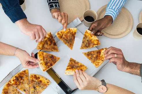 Von oben auf die Gesellschaft von anonymen multiethnischen Freunden, die am Tisch sitzen und leckere Pizza essen - ADSF28981