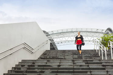 Sportswoman looking away while moving down on steps - EAF00081