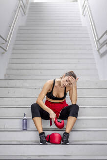 Tired female boxer sitting on steps - EAF00083