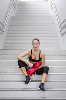 Selbstbewusste junge Sportlerin auf einer Treppe im Keller sitzend - EAF00086