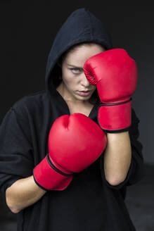 Determined young female athlete in red boxing gloves - EAF00097