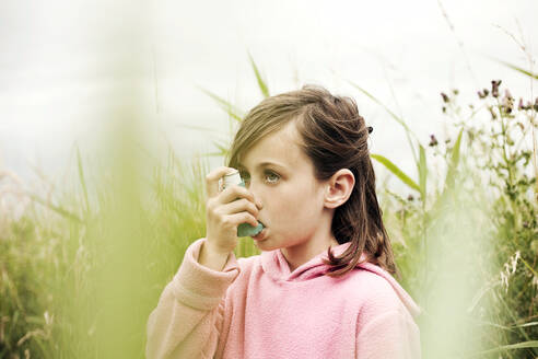 Mädchen im rosa Kapuzenpulli benutzt Asthma-Inhalator - AJOF01613
