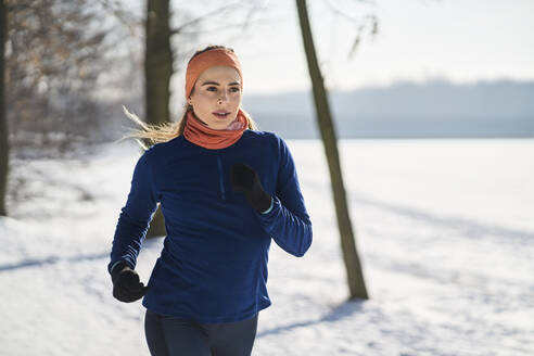 Young woman in sports clothing jogging during winter - BSZF01902