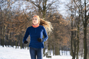 Junge Frau schaut beim Laufen im Winter weg - BSZF01907