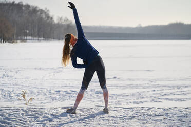 Woman stretching on snow - BSZF01917