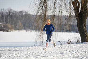 Frau läuft bei Sonnenschein auf Schnee - BSZF01922