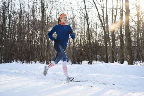 Junge Frau joggt im Schnee - BSZF01925