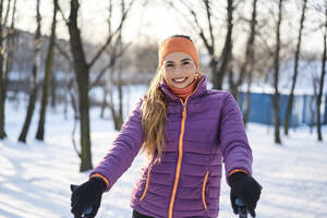 Junge Frau in wattierter Jacke lächelt im Winter - BSZF01931