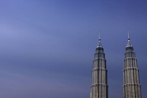 Malaysia, Kuala Lumpur, Petronas Towers standing against sky at dusk - EAF00107