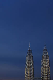 Malaysia, Kuala Lumpur, Petronas Towers standing against sky at dusk - EAF00109