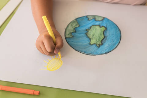 Girl drawing sun on cardboard paper at home stock photo