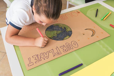 Girl drawing on cardboard paper at table in living room - JRVF01618