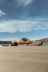 Sportswoman doing Matsyasana on jetty - OCAF00706