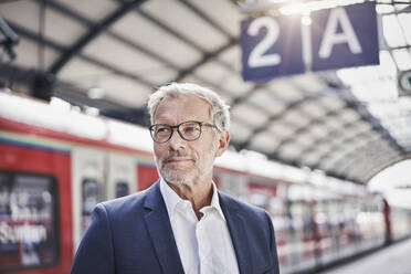 Businessman contemplating while standing at railroad station - RORF02832