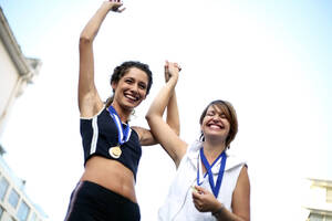 Glückliche weibliche Athleten mit Medaillen, die ihren Erfolg feiern - AJOF01619