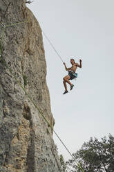 Männlicher Kletterer hängt am Seil auf einem Felsen - ACPF01281