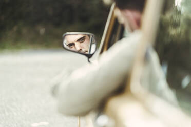 Spiegelung eines jungen Mannes im Seitenspiegel eines Autos - DGOF02275