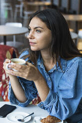 Pensive female freelance worker having coffee at cafe - PNAF02117