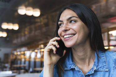 Schöne Freiberuflerin, die in einem Café mit ihrem Handy telefoniert - PNAF02135
