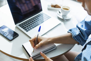 Female freelancer writing on diary at cafe - PNAF02142