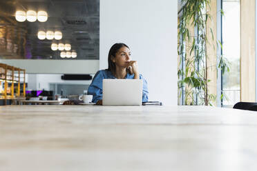 Businesswoman contemplating while sitting at table in cafe - PNAF02147