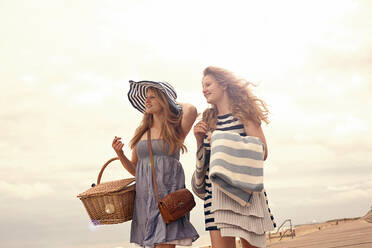 Lächelnde Freundinnen, die beim Spaziergang am Strand wegschauen - AJOF01627