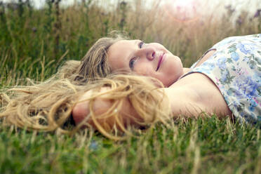 Smiling girl day dreaming while lying on grass - AJOF01635