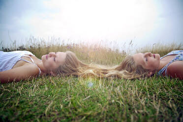 Freundinnen liegen mit geschlossenen Augen im Gras - AJOF01636