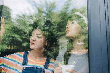 Friends looking through house window - ASGF01213