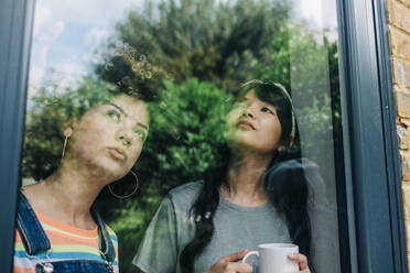 Young women looking through glass window - ASGF01214