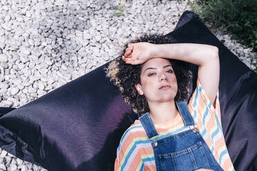 Woman relaxing on bean bag at backyard - ASGF01241