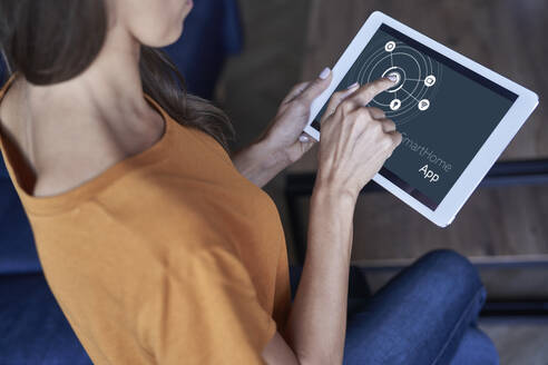 Frau, die eine Smart-Home-Anwendung auf einem digitalen Tablet zu Hause nutzt - ABIF01470