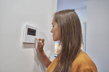 Frau benutzt Hausautomatisierungsgerät an der Wand - ABIF01489
