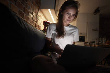 Frau benutzt Laptop, während sie zu Hause sitzt - ABIF01514