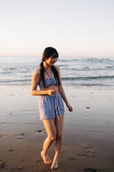 Glückliche junge Frau genießt am Strand im Urlaub - ASGF01275