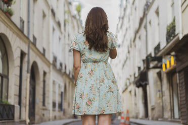 Junge Frau in blumengemustertem Kleid auf dem Fußweg stehend - AFVF09047