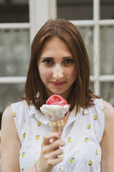 Lächelnde junge schöne Frau mit Eiscreme in der Hand - AFVF09070
